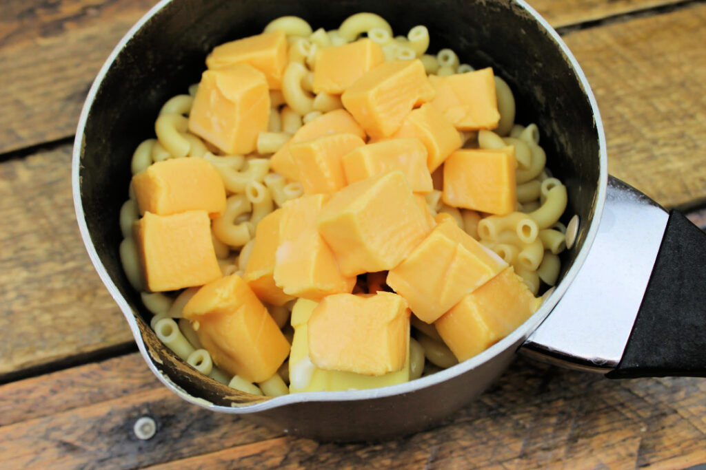 Cubed pasteurized cheese product and butter added to cooked elbow macaroni before stirring into a creamy homemade mac and cheese sauce.