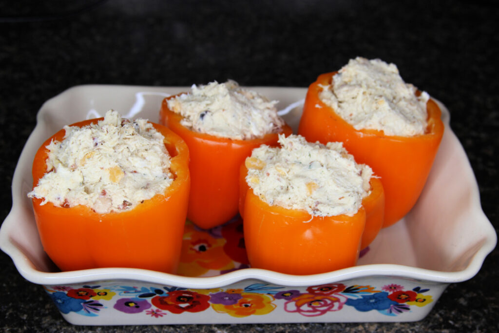 Bell peppers filled with a creamy chicken, bacon, ranch, and cheddar cheese mixture before baking in a casserole dish.