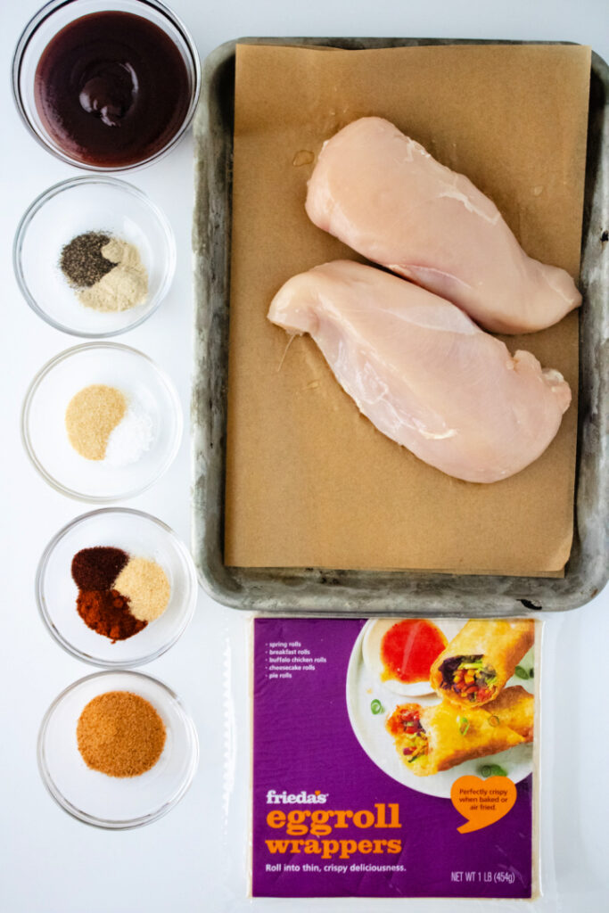 Chicken breasts, BBQ sauce, seasonings, and egg roll wrappers for making BBQ chicken egg rolls.