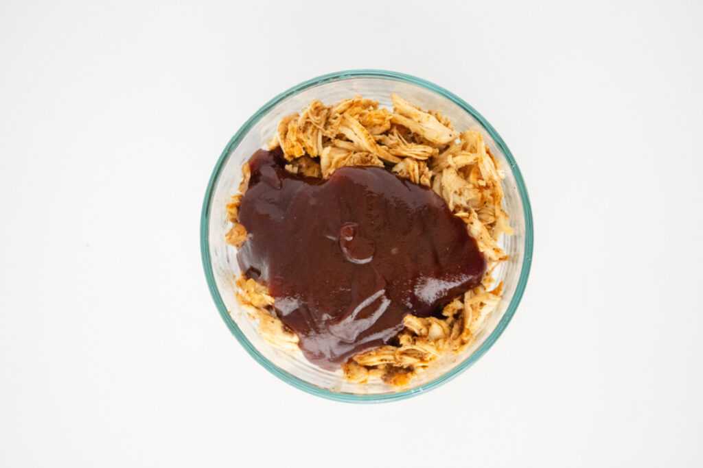 BBQ sauce added to shredded slow cooker chicken for the BBQ chicken egg roll filling.