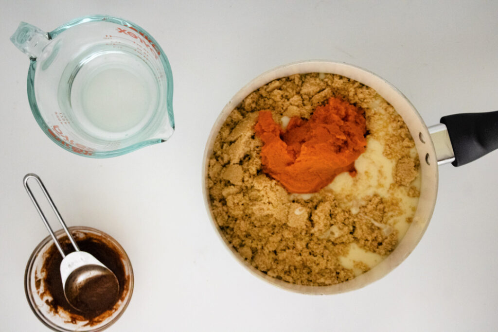 Sweetened condensed milk, brown sugar, pumpkin puree, and water added to a saucepan for homemade pumpkin spice syrup