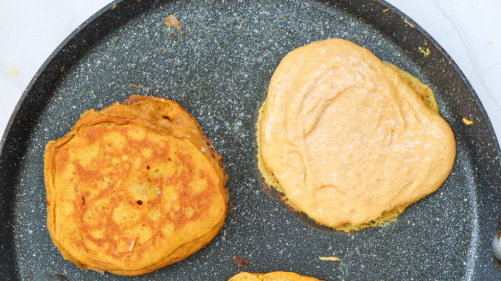 Pumpkin pancakes cooking until golden brown in a skillet