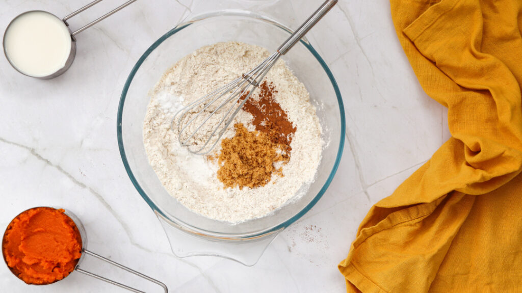Dry ingredients for pumpkin pancakes with brown sugar, cinnamon, and nutmeg in a mixing bowl