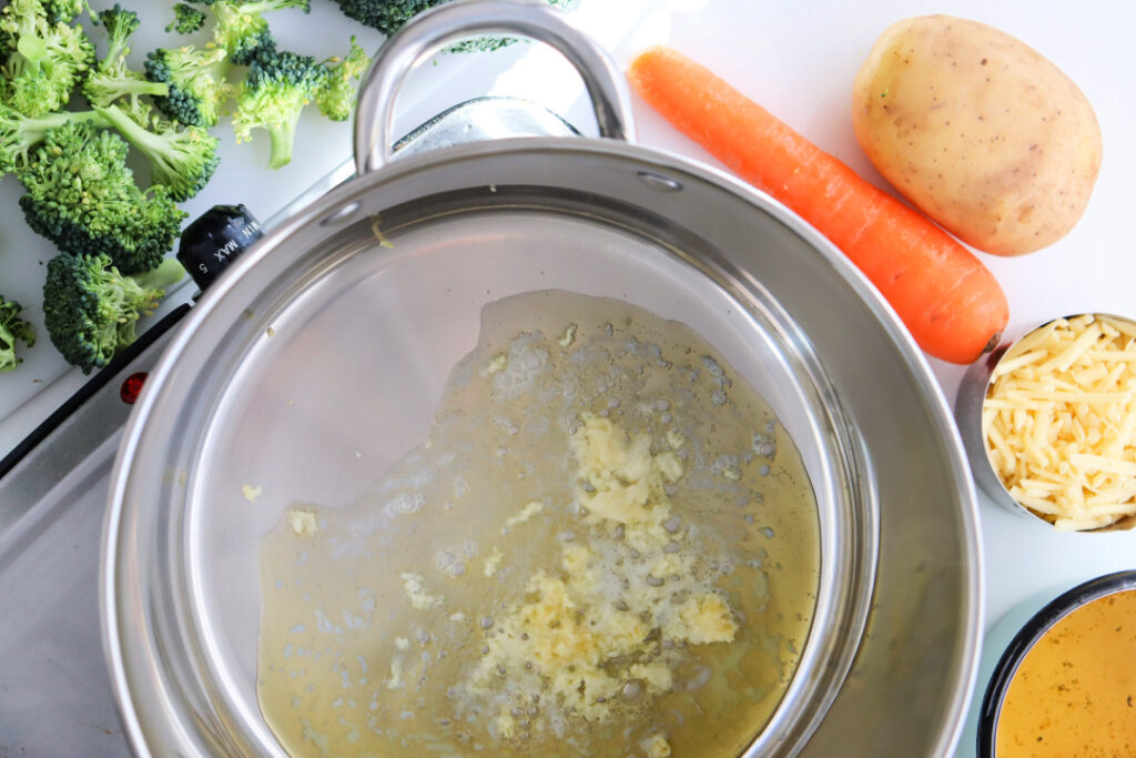 Butter and minced garlic sautéing in a Dutch oven for homemade Broccoli Cheddar Soup before adding the vegetables and broth.