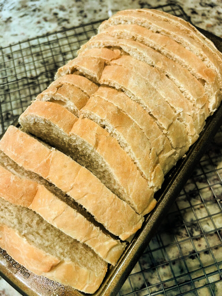 Freshly baked homemade basic white bread sliced into even pieces with a serrated bread knife after cooling completely.