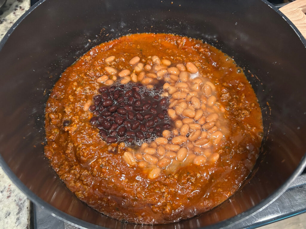 Undrained pinto beans and black beans added to the ground beef mixture for beef and bean chili.