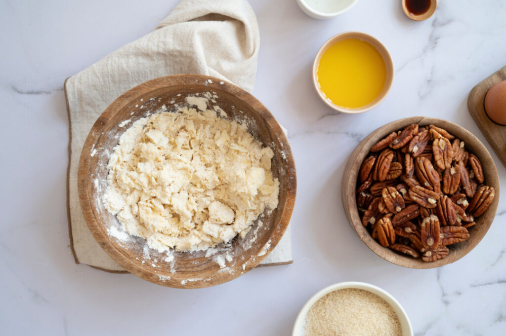 Cold butter cut into flour and salt until crumbly for the homemade crust of a classic pecan pie.