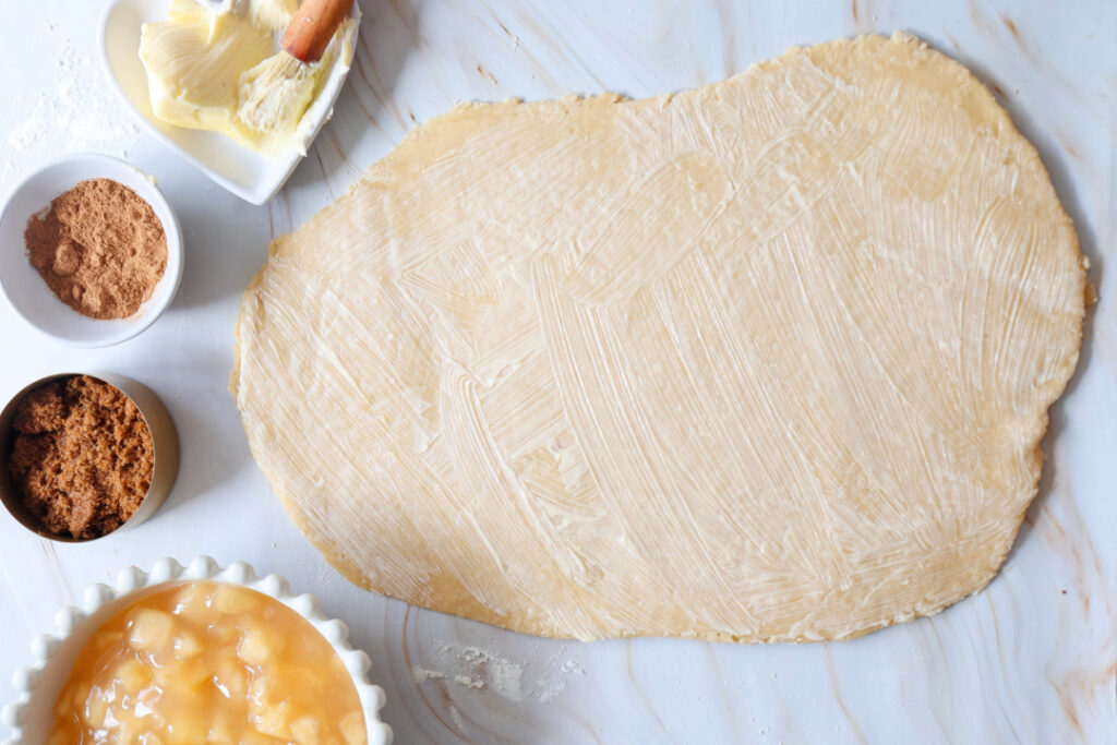 Softened butter spread evenly over rolled cinnamon roll dough before adding the cinnamon-sugar filling.