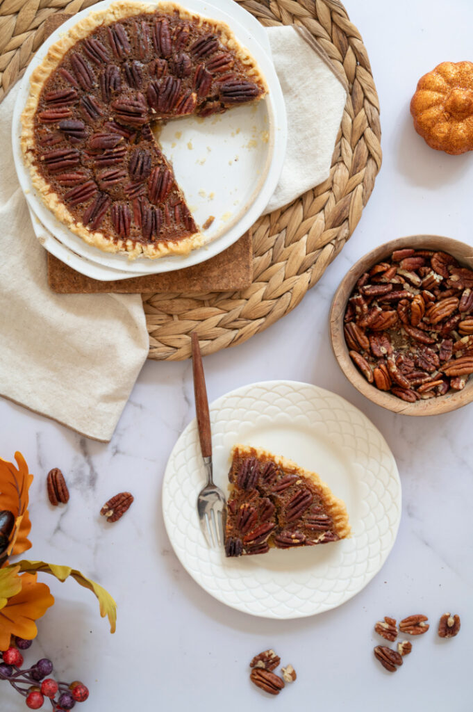 Homemade classic pecan pie with a slice served on a plate, showing the rich pecan filling and flaky crust.