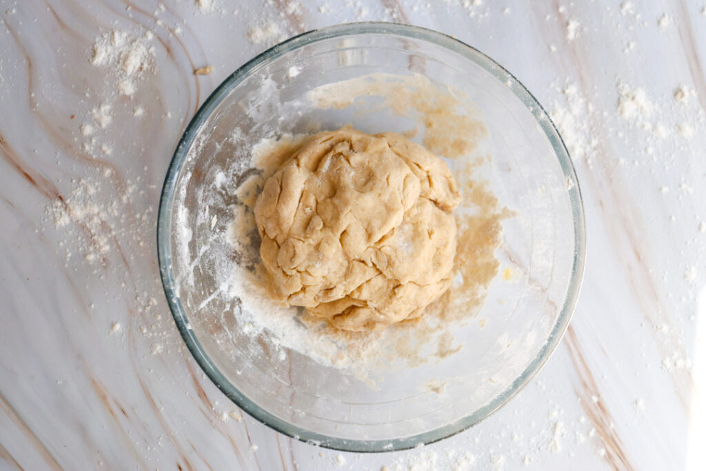 Ball of homemade cinnamon roll dough in a glass mixing bowl before rising.